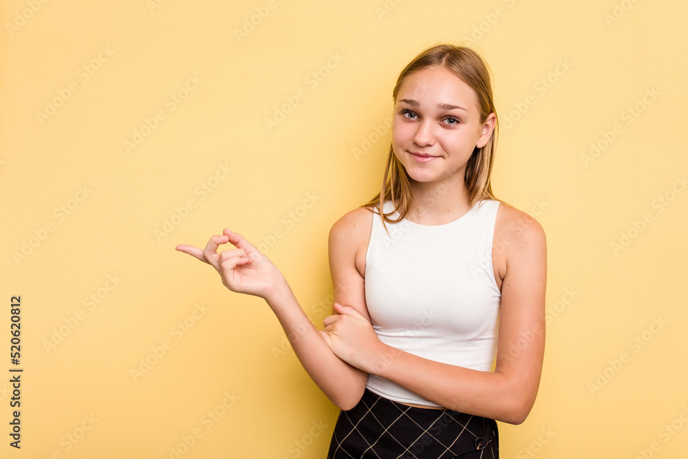 Young caucasian girl isolated on yellow background smiling cheerfully pointing with forefinger away. Young caucasian girl isolated on yellow background smiling cheerfully pointing with forefinger away.