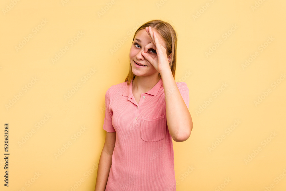 Young caucasian girl isolated on yellow background excited keeping ok gesture on eye. Young caucasian girl isolated on yellow background excited keeping ok gesture on eye.