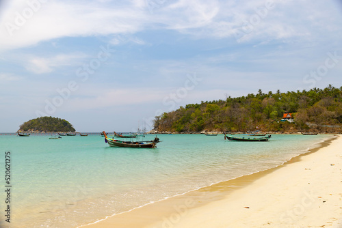 Phuket, Thailand - March 17, 2021: Wooden traditional boat at Kata Beach with crystal clear water, famous tourist destination and resort area in Southern of Thailand