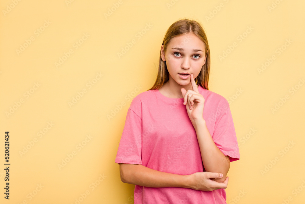 Young caucasian girl isolated on yellow background looking sideways with doubtful and skeptical expression.