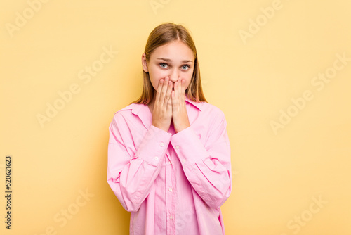 Young caucasian girl isolated on yellow background shocked, covering mouth with hands, anxious to discover something new.