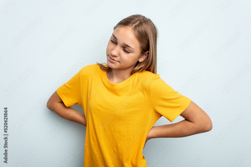Young caucasian girl isolated on blue background suffering a back pain. Young caucasian girl isolated on blue background suffering a back pain.