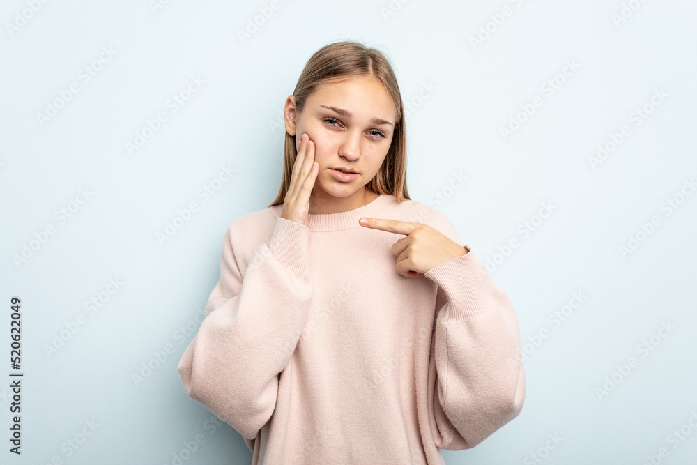 Young caucasian girl isolated on blue background having a strong teeth pain, molar ache. Young caucasian girl isolated on blue background having a strong teeth pain, molar ache.