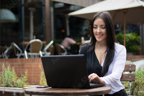 Young woman working outdoor, using a laptop computer in a cafe. © Cavan
