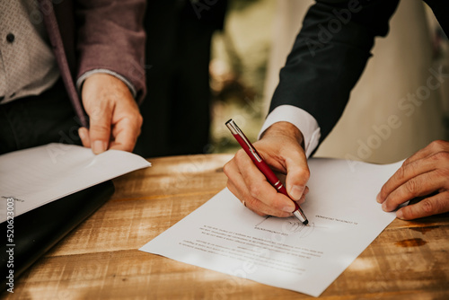 Groom's hand signing the registry at a civil wedding