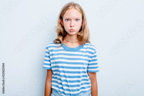 Caucasian teen girl isolated on blue background blows cheeks, has tired expression. Facial expression concept.