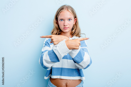 Caucasian teen girl isolated on blue background points sideways  is trying to choose between two options.