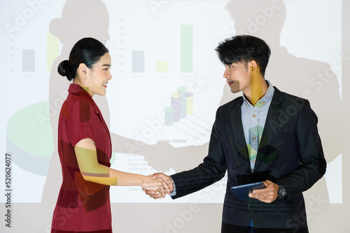 business partners shaking hands after concluding a business presentation finished. Business man and woman standing in front of Infographics Animation on Big Screen. Business to succeed concept.