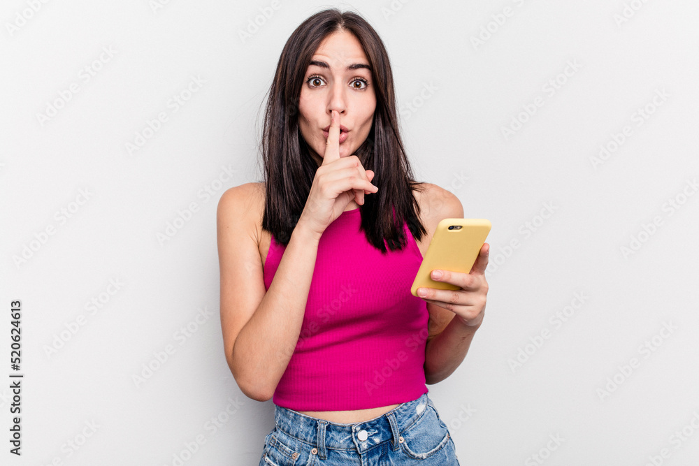 Young caucasian woman holding mobile phone isolated on white background keeping a secret or asking for silence. Young caucasian woman holding mobile phone isolated on white background keeping a secret or asking for silence.
