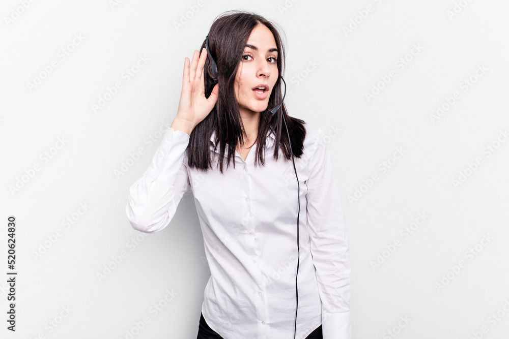 Telemarketer caucasian woman working with a headset isolated on white background trying to listening a gossip. Telemarketer caucasian woman working with a headset isolated on white background trying to listening a gossip.
