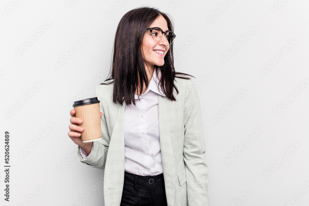 Young business caucasian woman holding takeaway coffee isolated on white background looks aside smiling, cheerful and pleasant.