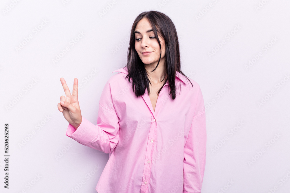 Young caucasian woman isolated on pink background joyful and carefree showing a peace symbol with fingers. Young caucasian woman isolated on pink background joyful and carefree showing a peace symbol with fingers.