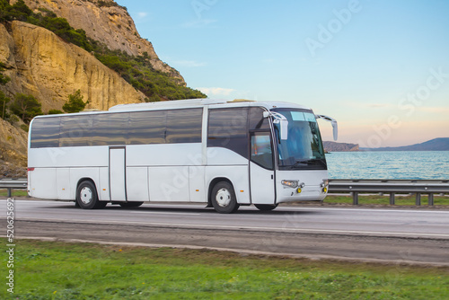 Tourist bus moves along the mountains on the sea photo
