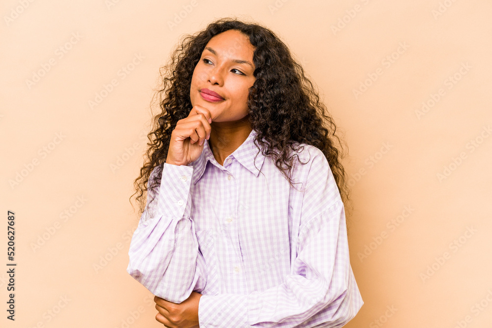 Young hispanic woman isolated on beige background thinking and looking up, being reflective, contemplating, having a fantasy. Young hispanic woman isolated on beige background thinking and looking up, being reflective, contemplating, having a fantasy.