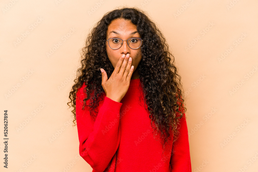 Young hispanic woman isolated on beige background shocked, covering mouth with hands, anxious to discover something new. Young hispanic woman isolated on beige background shocked, covering mouth with hands, anxious to discover something new.