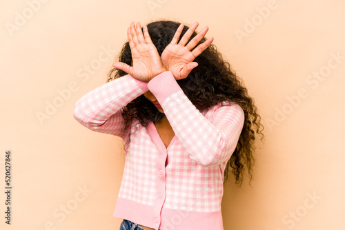 Young hispanic woman isolated on beige background keeping two arms crossed, denial concept.