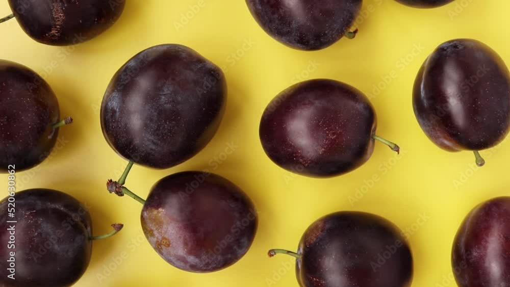 Ripe juicy plums on a yellow background. Top view. Rotate 360 degrees. Ripe juicy plums on a yellow background. Top view. Rotate 360 degrees.