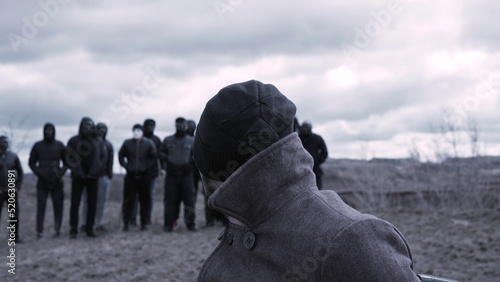Canvas Print Man sits in a chair and looks at a group of masked criminals