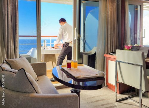Photography A room service waiter rings a full breakfast meal to a cruise ship stateroom cabin and balcony with the blue sea in view