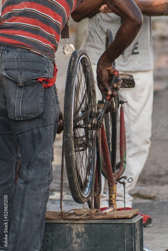 Photography Vertical shot of a man fixing a bicycle on the street