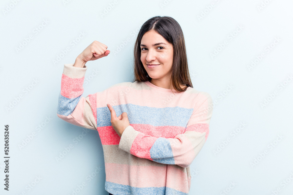 Young caucasian woman isolated on blue background showing strength gesture with arms, symbol of feminine power Young caucasian woman isolated on blue background showing strength gesture with arms, symbol of feminine power