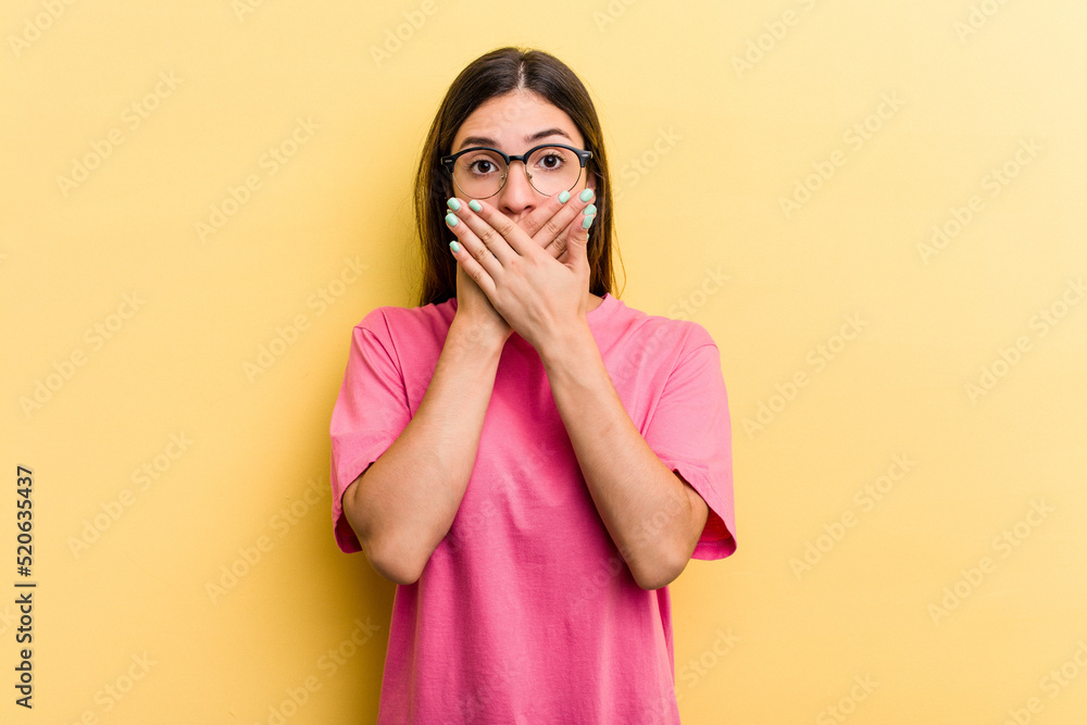 Young caucasian woman isolated on yellow background shocked covering mouth with hands. Young caucasian woman isolated on yellow background shocked covering mouth with hands.