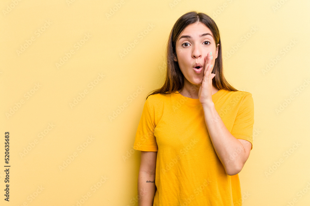 Young caucasian woman isolated on yellow background is saying a secret hot braking news and looking aside Young caucasian woman isolated on yellow background is saying a secret hot braking news and looking aside