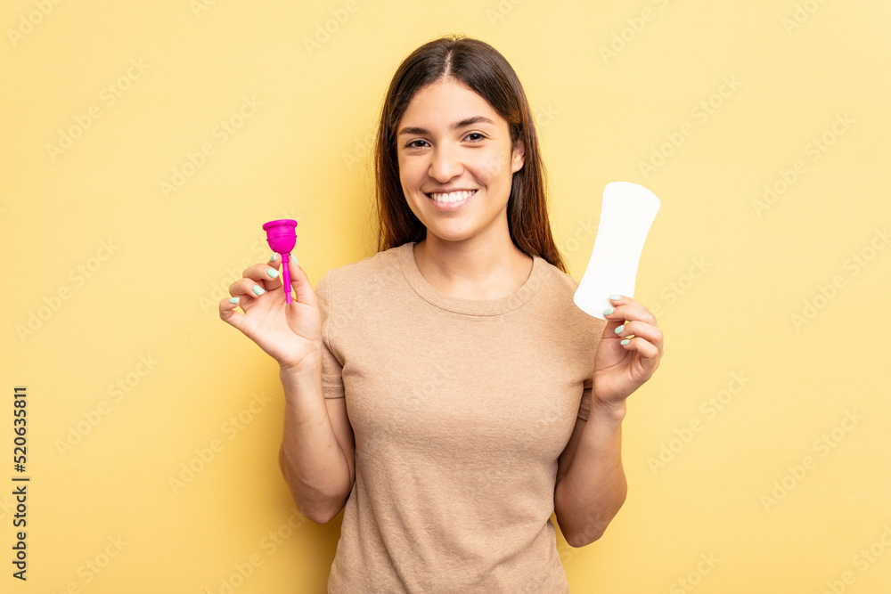 Young caucasian woman holding a menstrual cup isolated on yellow background Young caucasian woman holding a menstrual cup isolated on yellow background