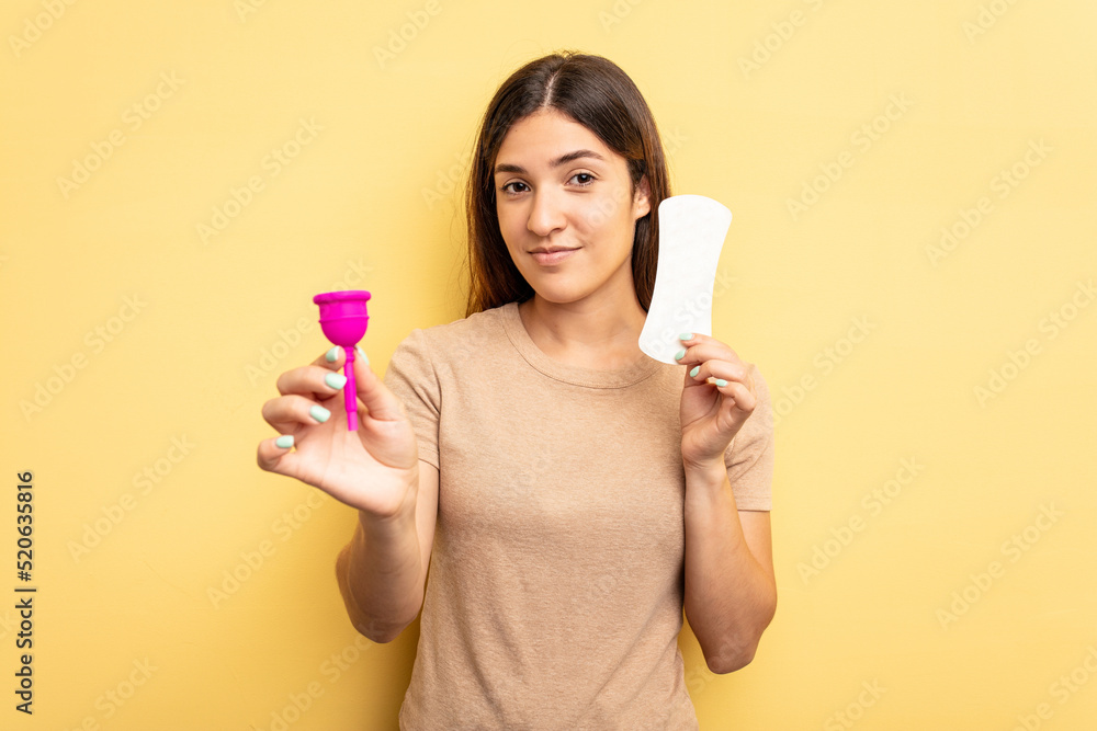 Young caucasian woman holding a menstrual cup isolated on yellow background Young caucasian woman holding a menstrual cup isolated on yellow background
