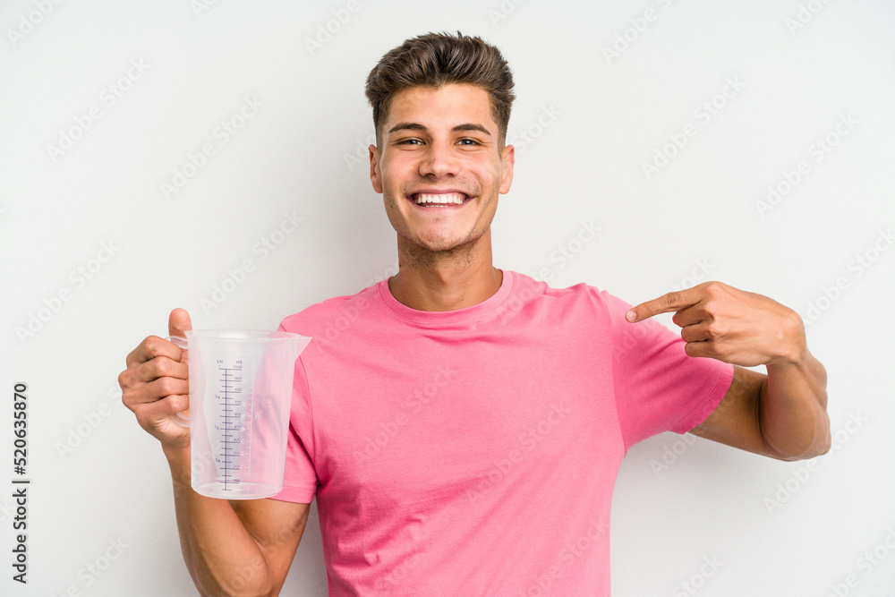 Young caucasian man holding measuring jug isolated on white background person pointing by hand to a shirt copy space, proud and confident Young caucasian man holding measuring jug isolated on white background person pointing by hand to a shirt copy space, proud and confident