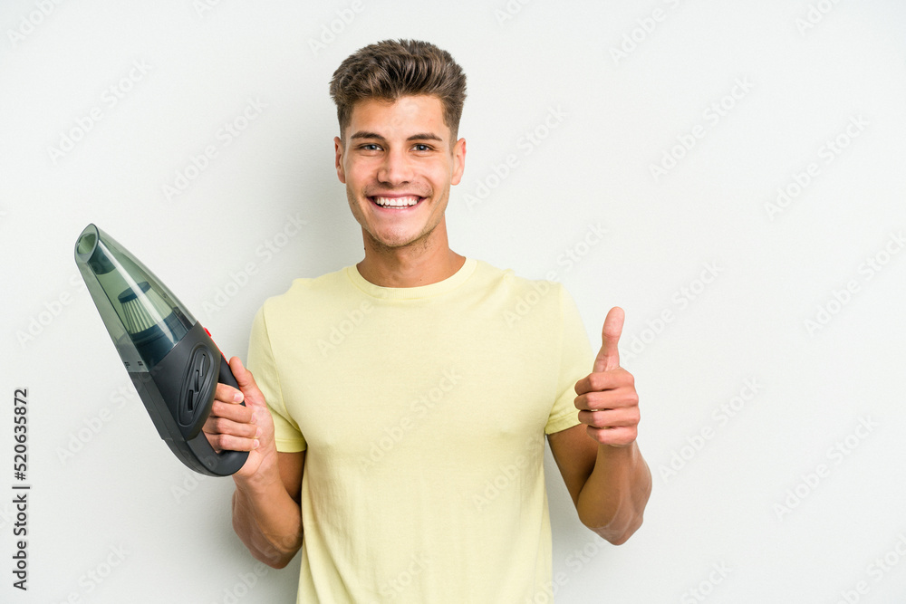 Young caucasian man holding a hand vacuum cleaner isolated on white background smiling and raising thumb up Young caucasian man holding a hand vacuum cleaner isolated on white background smiling and raising thumb up