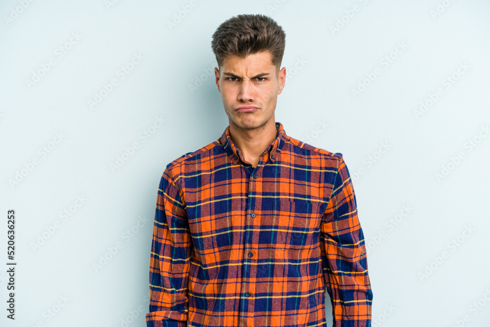 Young caucasian man isolated on blue background sad, serious face, feeling miserable and displeased.