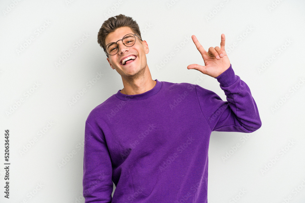 Young caucasian man isolated on white background showing a horns gesture as a revolution concept. Young caucasian man isolated on white background showing a horns gesture as a revolution concept.
