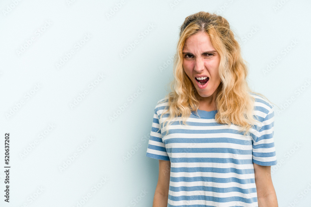 Young caucasian woman isolated on blue background shouting very angry, rage concept, frustrated. Young caucasian woman isolated on blue background shouting very angry, rage concept, frustrated.