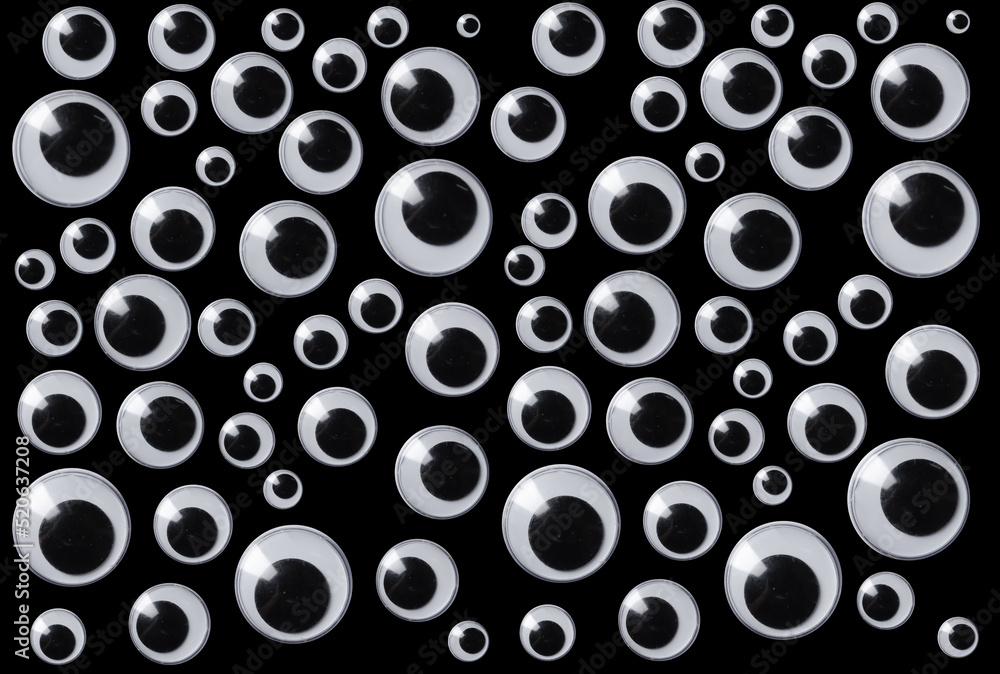 Googly eyes are small plastic craft supplies used to imitate eyeballs  isolated on black background. Stock Photo
