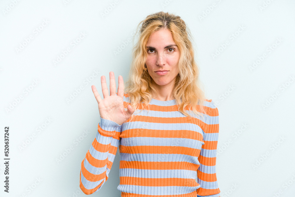 Young caucasian woman isolated on blue background smiling cheerful showing number five with fingers. Young caucasian woman isolated on blue background smiling cheerful showing number five with fingers.