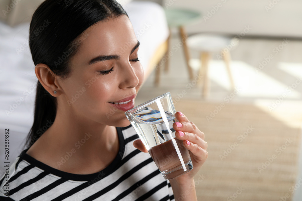 Young woman drinking water indoors, space for text. Refreshing drink Young woman drinking water indoors, space for text. Refreshing drink