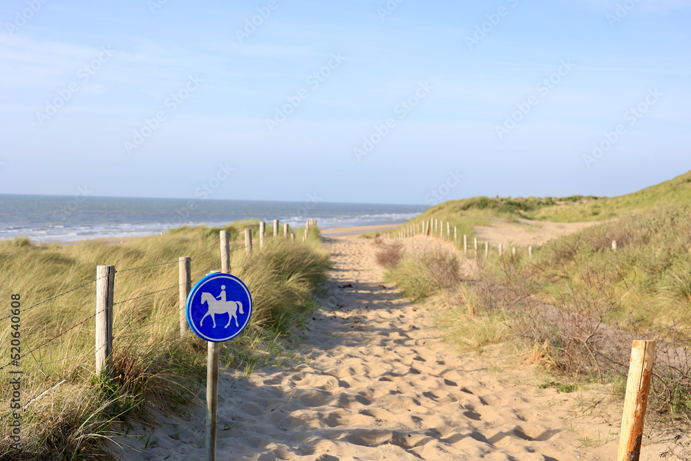 Sign of a horse riding path. View from dune top over sunset in North Sea. The Meijendel, Nature preserve in Wassenaar. South Holland, The Netherlands. 