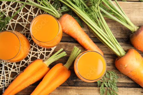 Freshly made carrot juice on wooden table, flat lay