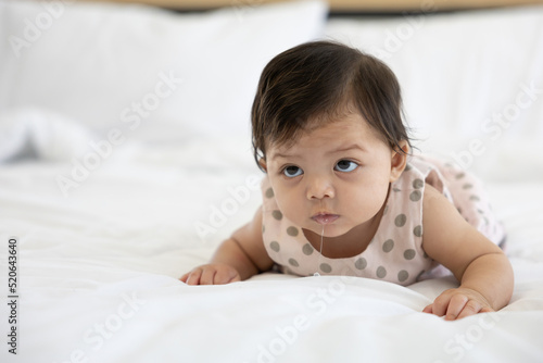 cute baby crawling on bed and drooling from mouth