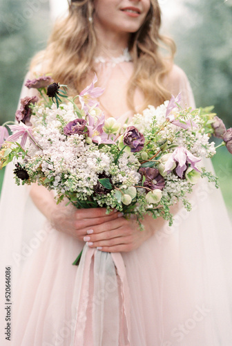 Wedding bouquet of wild flowers in the hands of the bride. Close-up