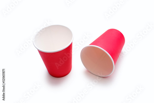 Two disposable red cups for coffee and drinks made of cardboard on a white background. Top view of two red coffee cups with custom placement