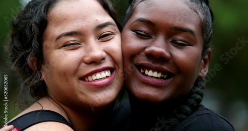 Two interracial girlfriends hugging each other, close-up interracial faces embrace