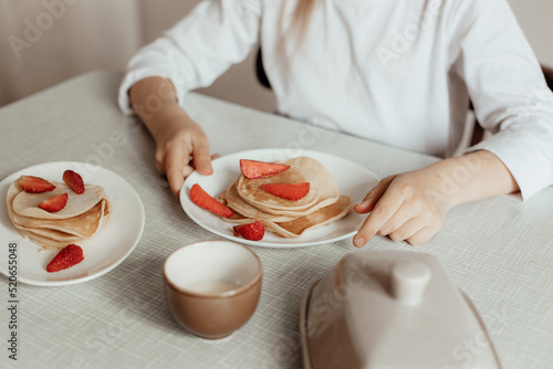 Hungry little girl eat sweet panckaces with strawberries. Family breakfast concept photo