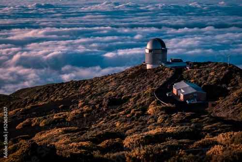Astronomical telescope on top of the mountain with the sea of ​​clouds in the background and sunset light