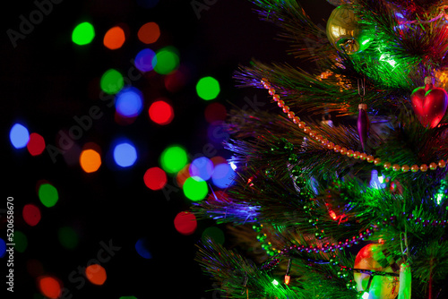 Christmas tree with toys and garlands stands in dark room.... © glebchik