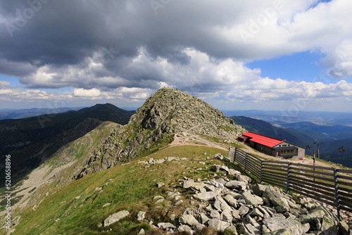 Chopok, Nizke Tatry, Low Tatras, Slovakia, Europe - mountain cabin and under top, peak and summit of the rocky mountain. Hikers on the top of hill. Wide angle with soft corners. photo