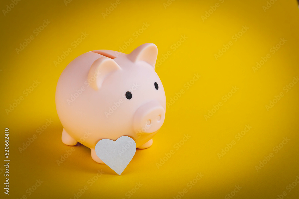 Saving money. The hand puts a heart in a piggy bank. Salary retention.