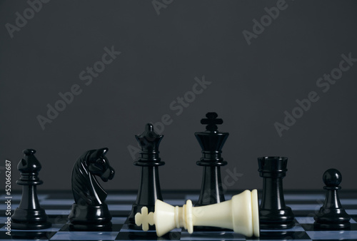 Standing black chess pieces and lying white king.