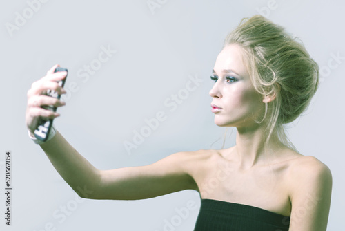 Girl with beautiful make-up makes selfie in the studio.